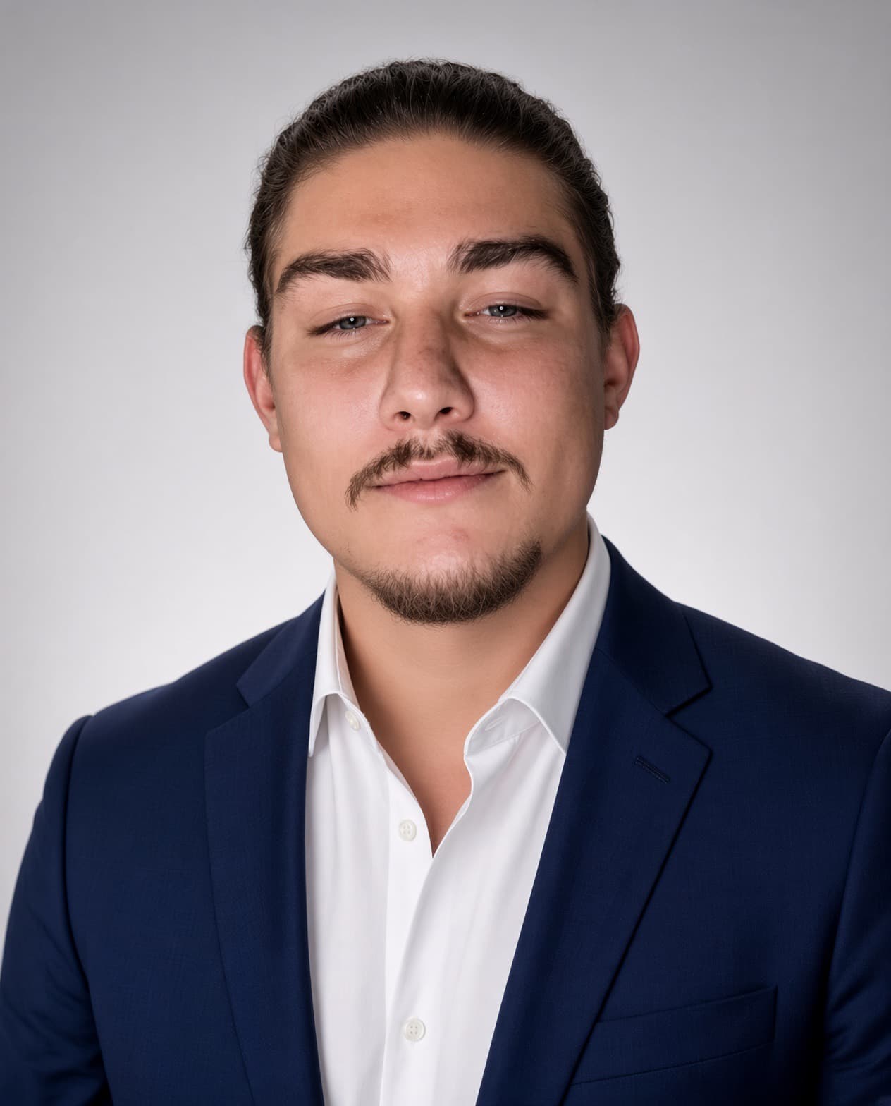 Professional headshot of a man with a mustache wearing a blue suit and white shirt.